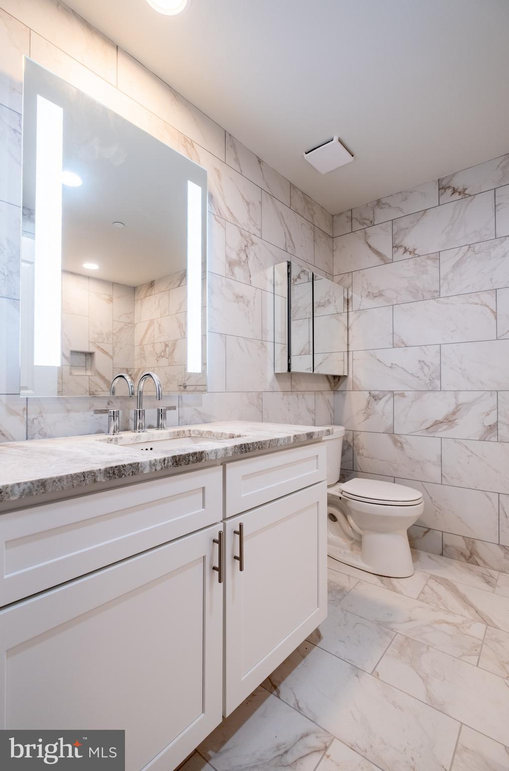 2301-61 John F Kennedy Boulevard, Unit 201 Philadelphia, PA 19103 - Photo 14 of 36 a bathroom with a granite countertop toilet sink and mirror