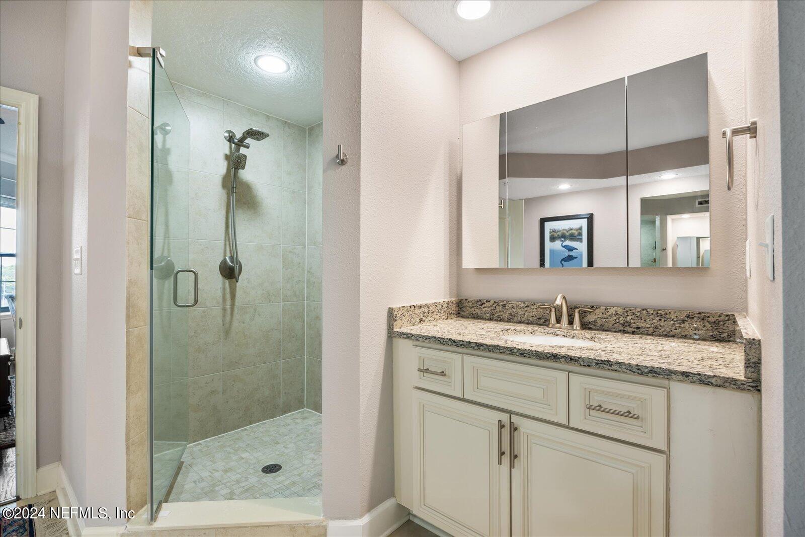 3958 Baymeadows Road, Unit 4501 Jacksonville, FL 32217 - Photo 38 of 57 a bathroom with a granite countertop sink a mirror and a shower