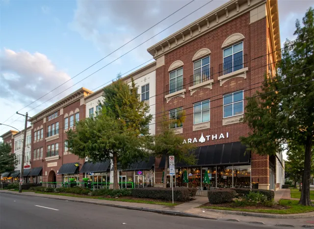 a view of a building with a street sign and a large tree