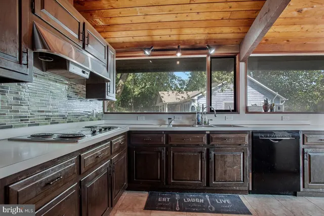 a kitchen with stainless steel appliances granite countertop a sink a stove window and cabinets