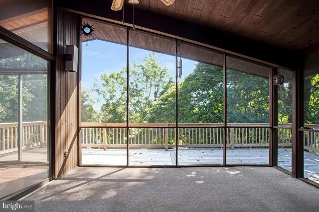 a view of a deck with a floor to ceiling window and wooden fence