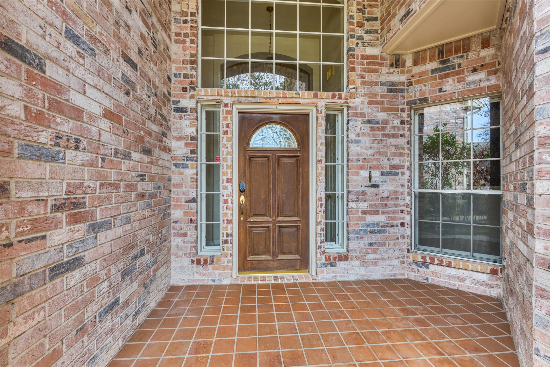 14420 Walters Road, Unit 26 Houston, TX 77014 - Photo 5 of 45 This inviting entryway features a warm brick exterior, a wooden door with glass accents, and large windows that allow for natural light, creating a welcoming and bright atmosphere.