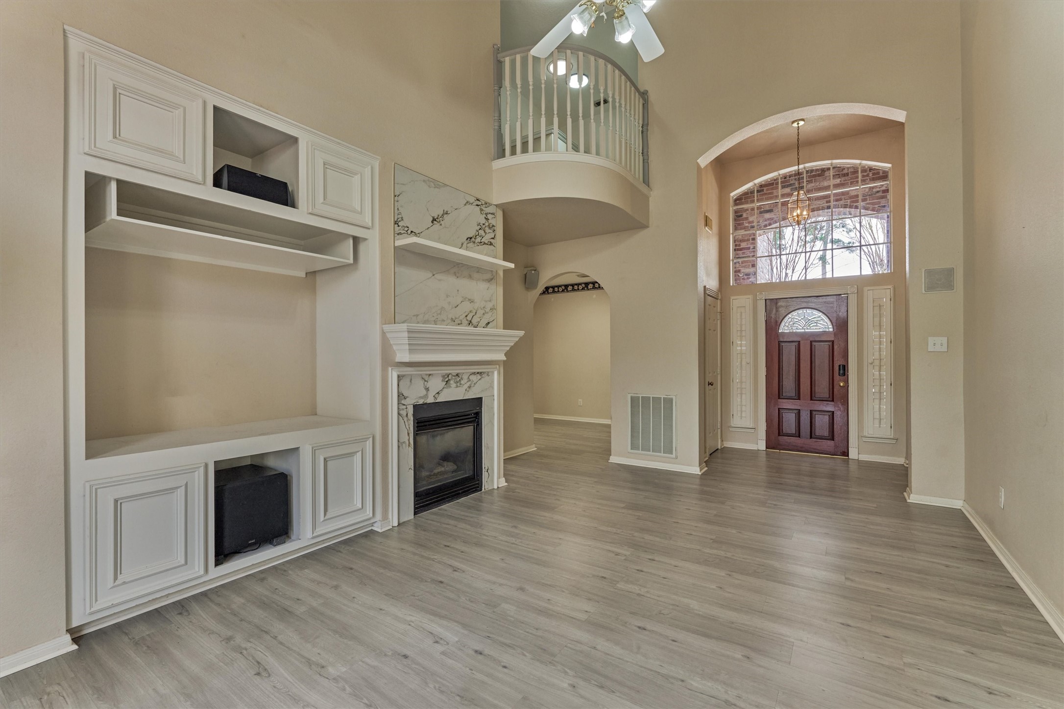 14420 Walters Road, Unit 26 Houston, TX 77014 - Photo 10 of 45 This spacious living area features high ceilings, light wood flooring, and a welcoming fireplace with built-in shelving. The grand entryway has a stylish front door with a large window above, flooding the space with natural light. The game room balcony overlooks the living room, adding a touch of sophistication.