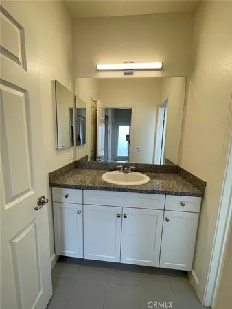 a bathroom with a granite countertop sink and a mirror