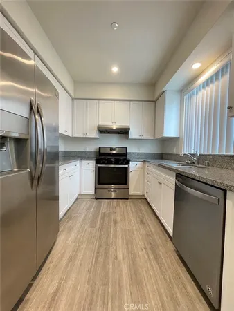 a kitchen with granite countertop a refrigerator stove top oven and sink