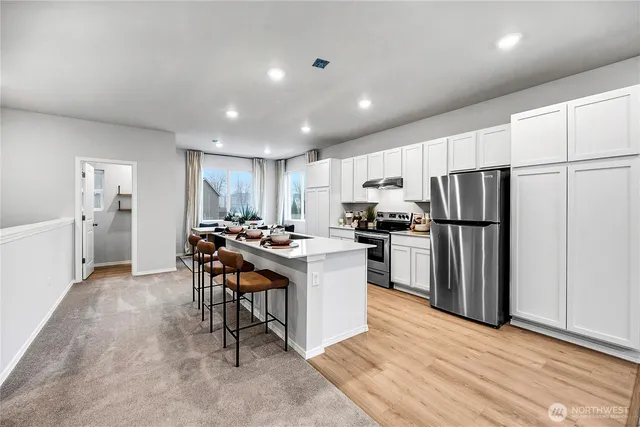 a kitchen with kitchen island a refrigerator stove a sink and a oven with wooden floor