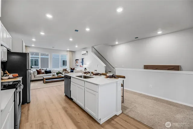 a kitchen with stainless steel appliances a stove a sink a refrigerator and chairs