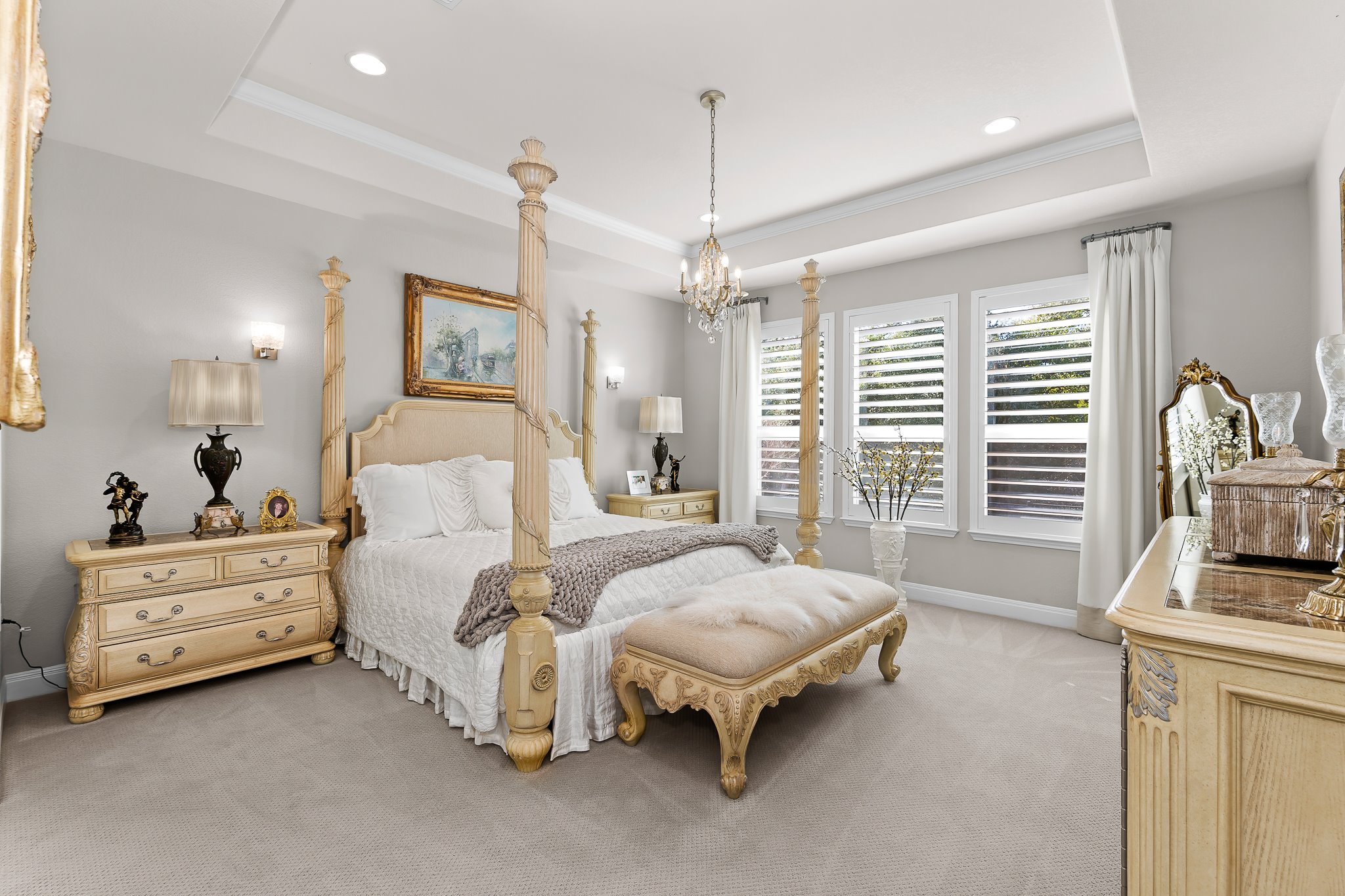 104 Marfa Cove Georgetown, TX 78633 - Photo 3 of 40 Elegant primary bedroom with tray ceiling, chandelier, custom drapes and a bank of windows for the natural light
