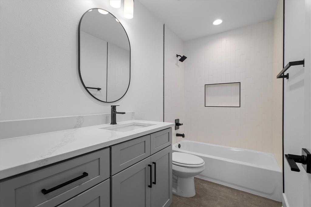 8918 Lowell Street Rowlett, TX 75089 - Photo 26 of 30 a bathroom with a granite countertop toilet a sink and a mirror