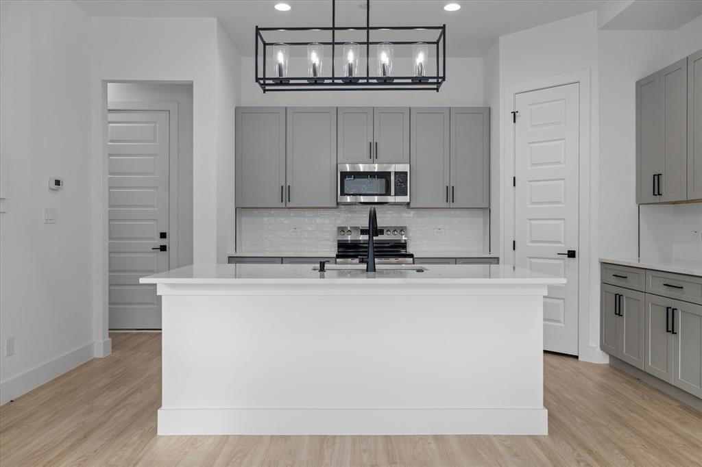8918 Lowell Street Rowlett, TX 75089 - Photo 6 of 30 a kitchen with kitchen island white cabinets and stainless steel appliances