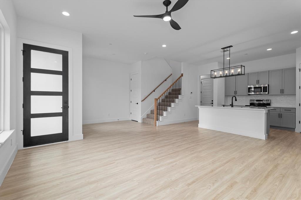 8918 Lowell Street Rowlett, TX 75089 - Photo 7 of 30 an empty room with wooden floor staircase and kitchen view