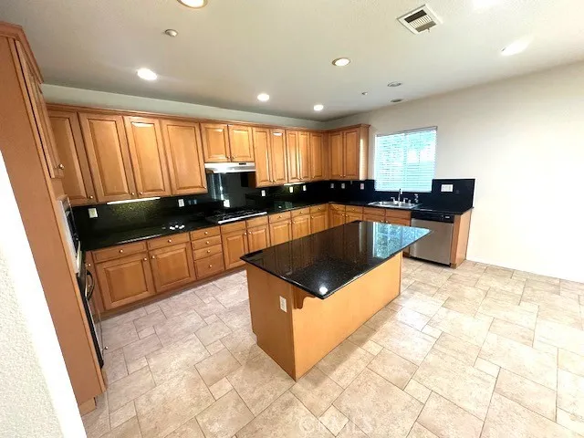 a kitchen with kitchen island granite countertop a sink a counter top space and cabinets