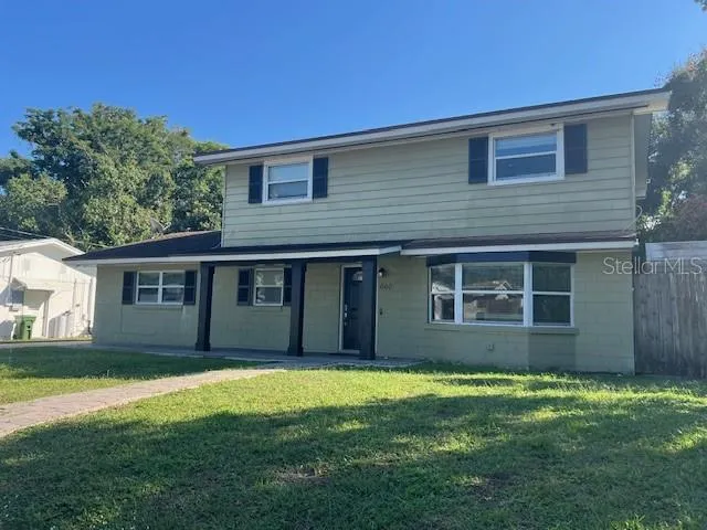 a house that has a big yard large trees with wooden fence