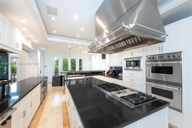 a large white kitchen with a stove a sink a refrigerator and cabinets