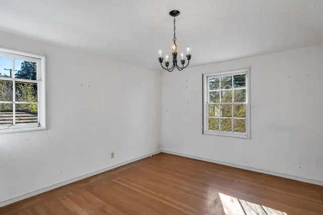 a view of an empty room with wooden floor and windows