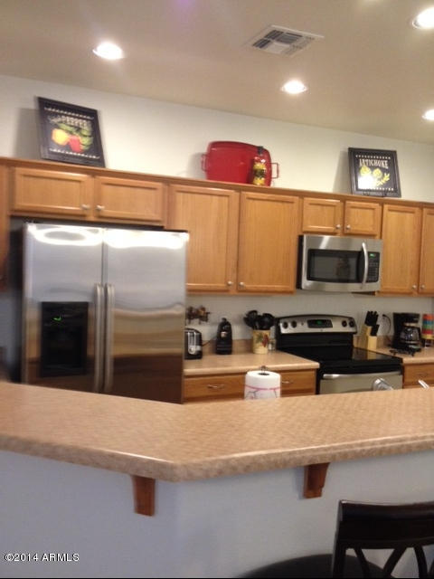 1250 South Rialto, Unit 62 Mesa, AZ 85209 - Photo 10 of 24 a kitchen with stainless steel appliances a refrigerator a stove and wooden cabinets