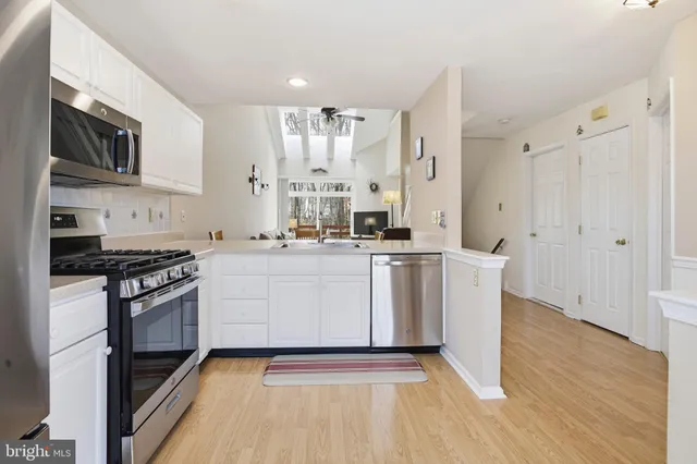 a kitchen with stainless steel appliances a white stove top oven cabinets and a wooden floor