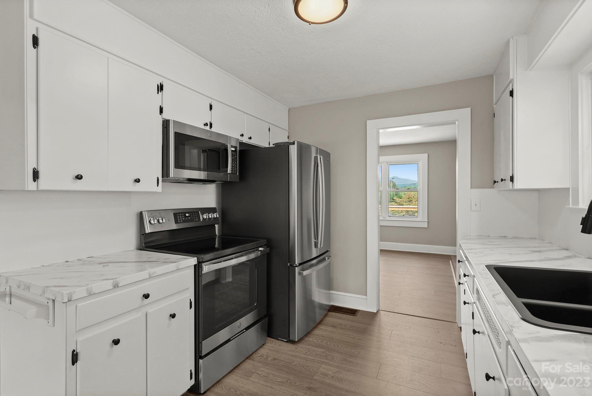 185 Substation Road Canton, NC 28716 - Photo 11 of 32 a kitchen with white cabinets and stainless steel appliances