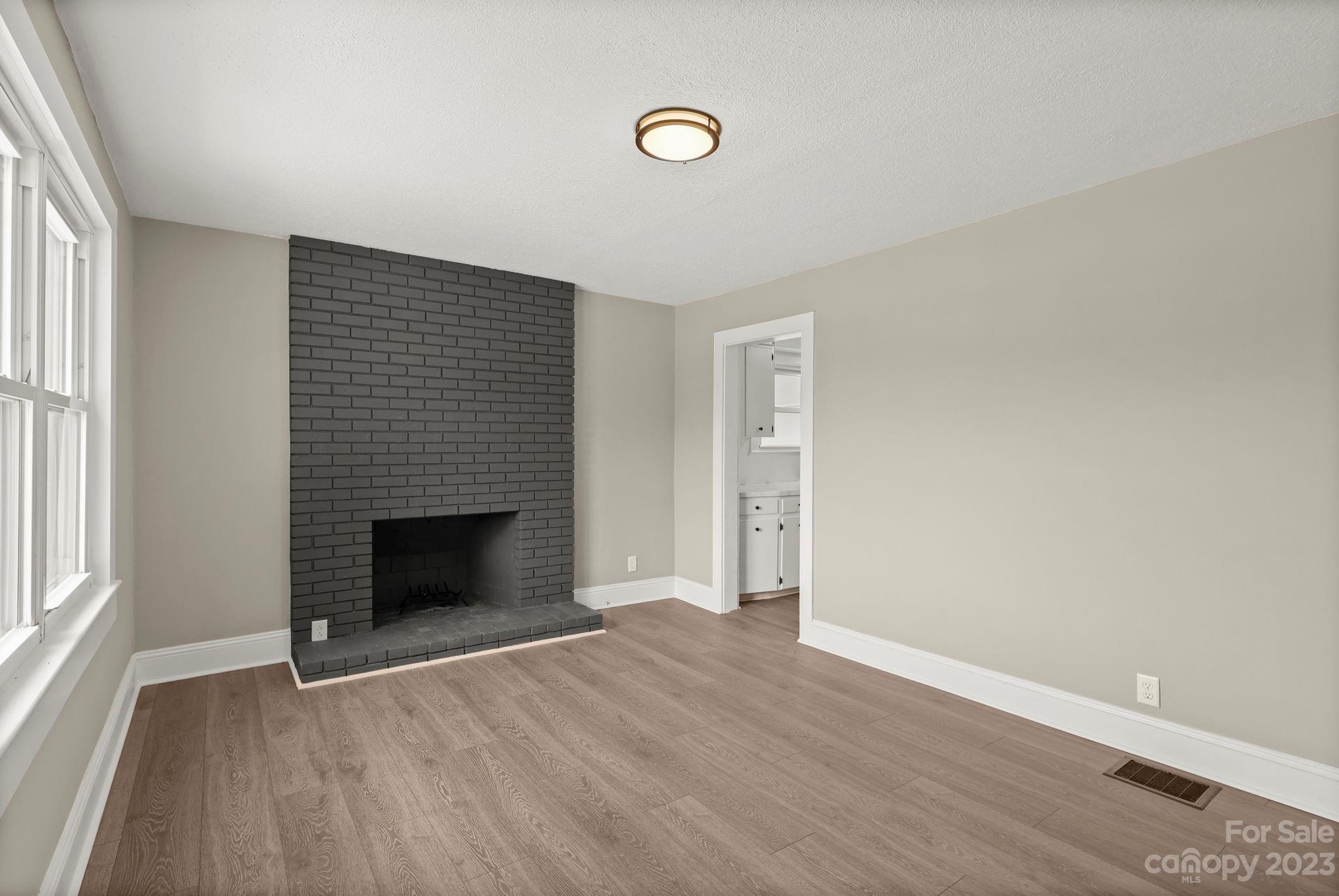 185 Substation Road Canton, NC 28716 - Photo 6 of 32 an empty room with wooden floor fireplace and windows