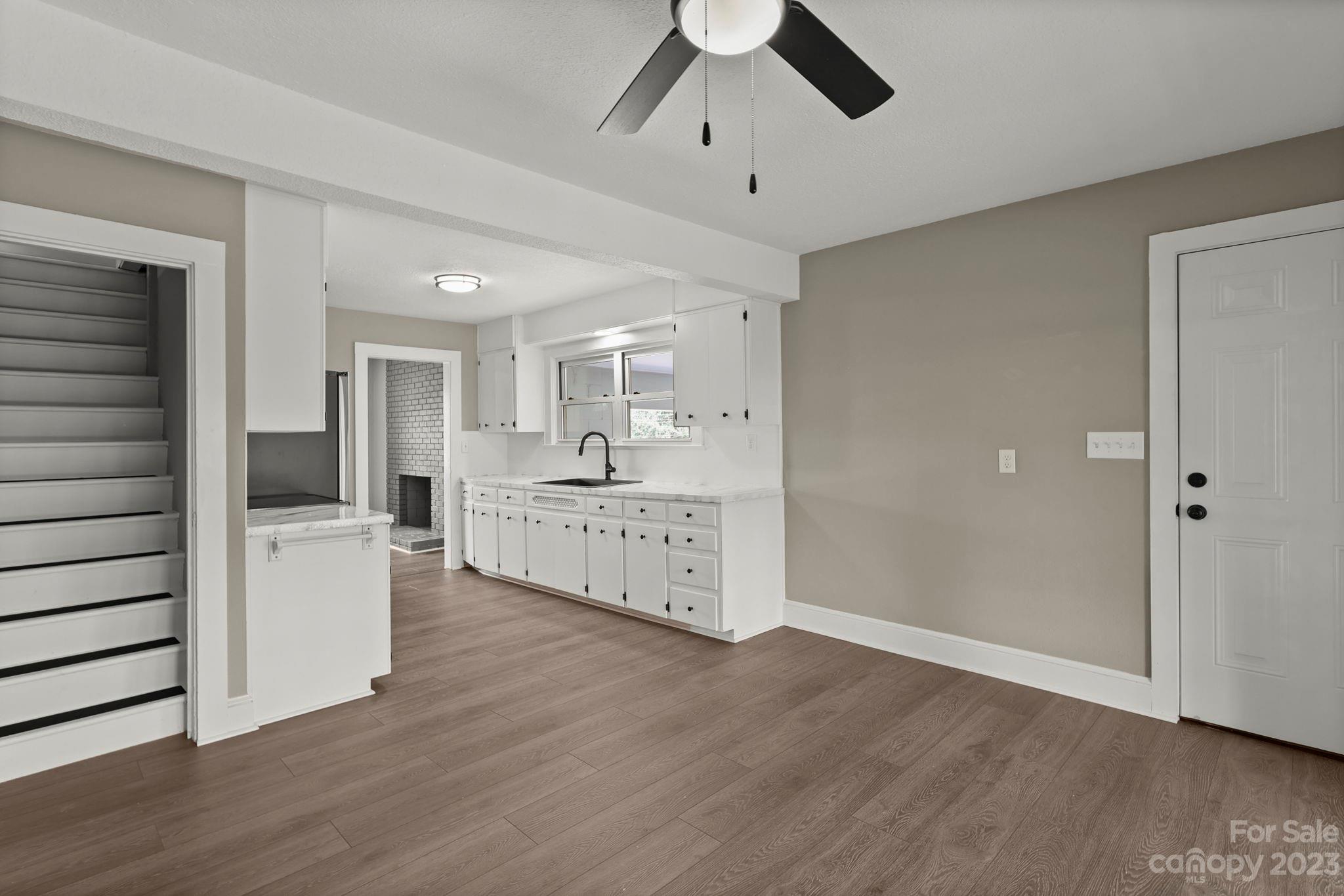 185 Substation Road Canton, NC 28716 - Photo 9 of 32 a large white kitchen with a refrigerator a stove top oven a white counter space and wooden floor