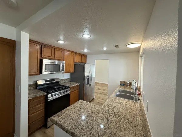 a kitchen with stainless steel appliances granite countertop a stove a sink and a refrigerator