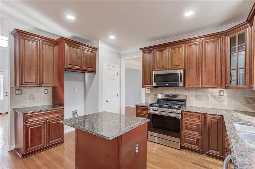 1446 Chadwick Ridge Court Lawrenceville, GA 30043 - Photo 15 of 54 a kitchen with stainless steel appliances granite countertop a stove top oven a sink dishwasher and a refrigerator with wooden cabinets
