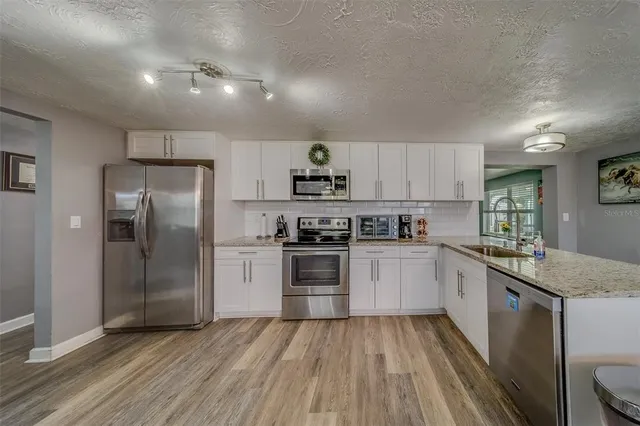 a kitchen with granite countertop a refrigerator stove top oven and sink