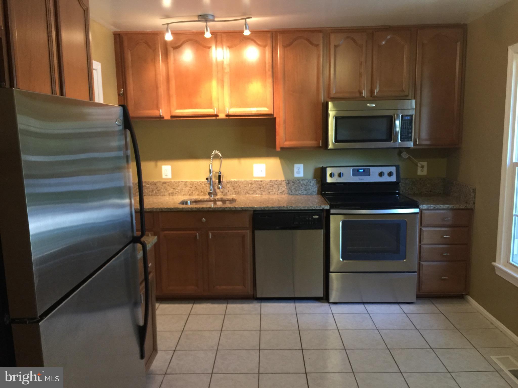 8029 Carbondale Way Springfield, VA 22153 - Photo 3 of 30 a kitchen with stainless steel appliances granite countertop a stove a sink and a microwave
