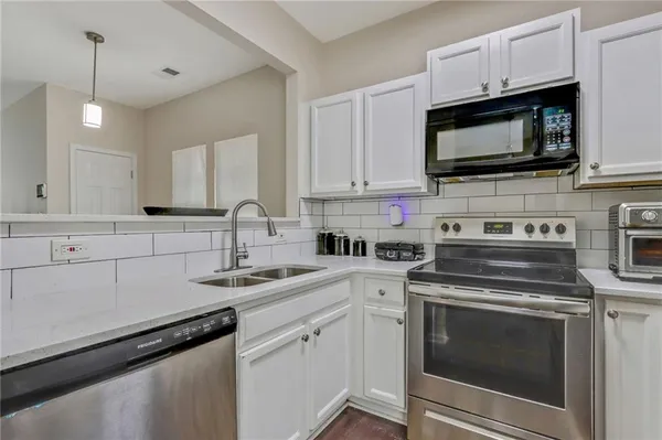 a kitchen with white cabinets and stainless steel appliances