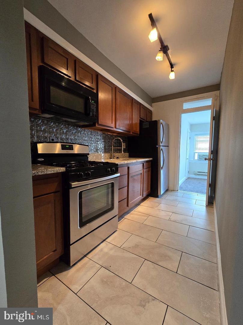 4044 7th Street Northeast, Unit 4 Washington, DC 20017 - Photo 2 of 9 a kitchen with stainless steel appliances granite countertop a stove cabinets and a refrigerator