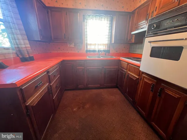 a kitchen with stainless steel appliances a refrigerator a sink a stove and wooden floors