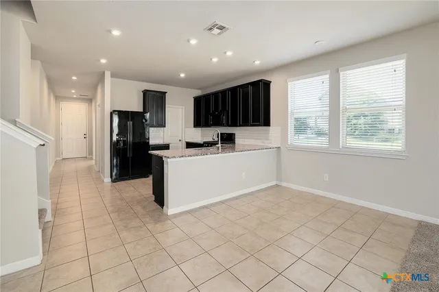a view of a kitchen with a sink and dishwasher a refrigerator with white cabinets