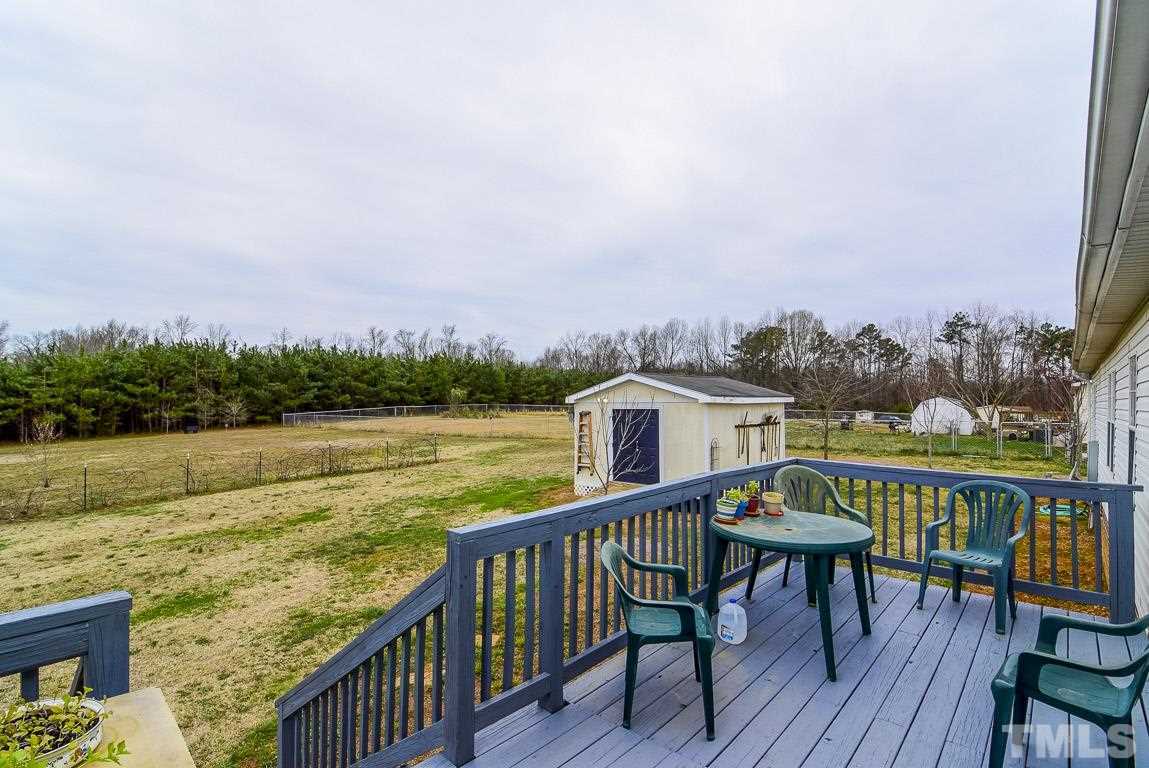 10129 Smith Road Middlesex, NC 27557 - Photo 9 of 25 a view of a roof deck with table and chairs a barbeque with wooden floor and fence