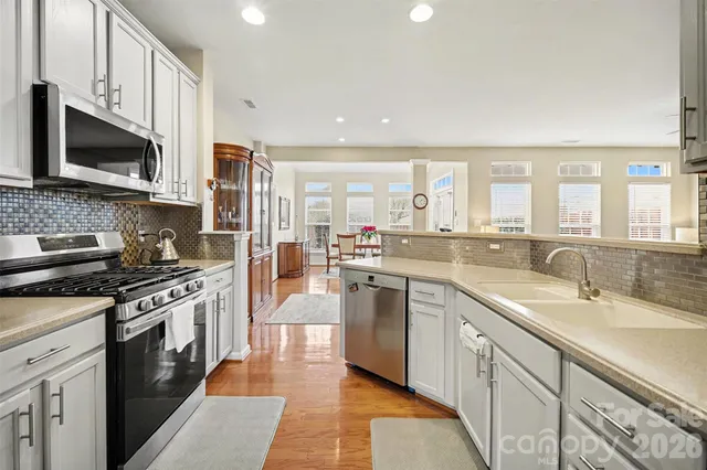 a kitchen with stainless steel appliances granite countertop a stove a sink and a microwave