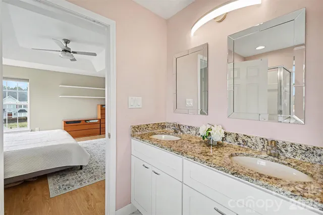 a en suite bathroom with a granite countertop sink and mirror