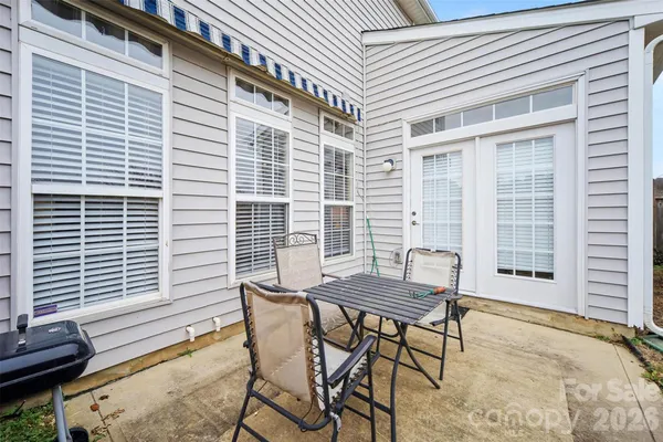 a patio with table and chairs and potted plants