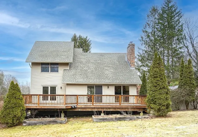 a front view of a house with a yard large tree and plants