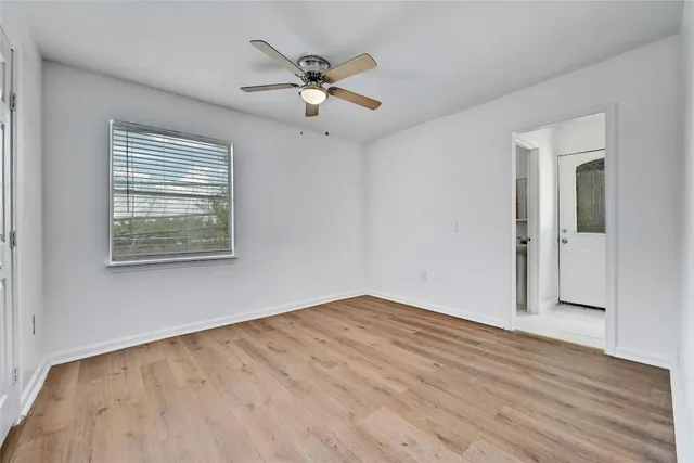a view of an empty room with wooden floor and a window