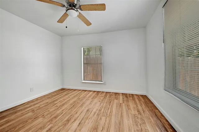 a view of empty room with wooden floor and fan