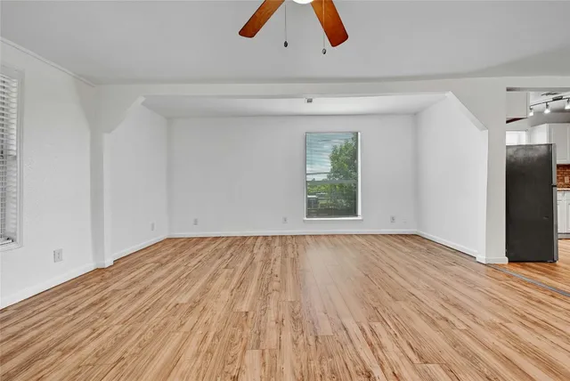 a view of an empty room with wooden floor and windows