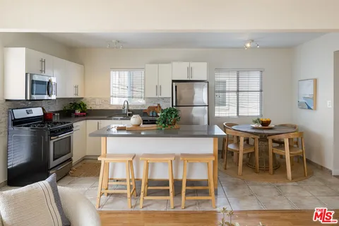 a kitchen with stainless steel appliances granite countertop a stove a sink a microwave a dining table and chairs