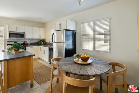 a kitchen with stainless steel appliances a dining table and a refrigerator