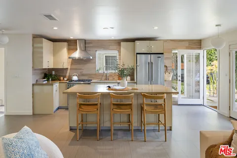 a kitchen with kitchen island granite countertop wooden cabinets and refrigerator