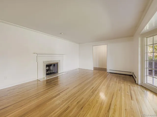 a view of empty room with wooden floor and fireplace