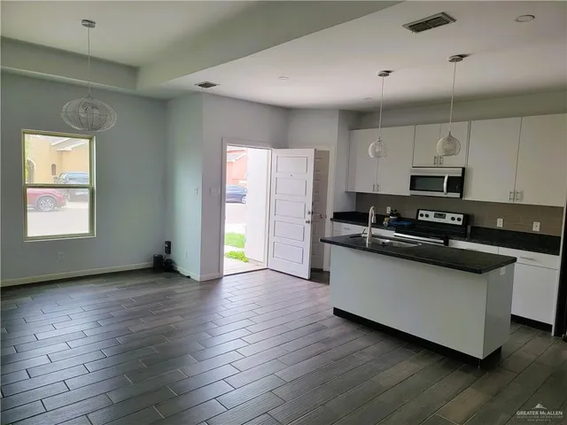 a kitchen with stainless steel appliances granite countertop a stove a sink and a microwave