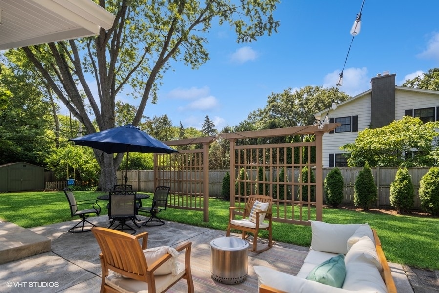 527 Maple Lane Geneva, IL 60134 - Photo 10 of 42 a view of a patio with couches table and chairs under an umbrella with a small yard