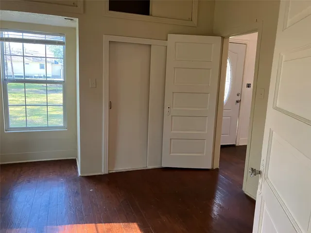 an empty room with wooden floor closet and windows