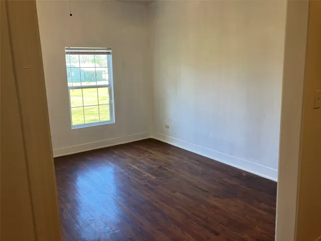 an empty room with wooden floor and window