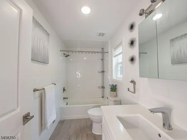a bathroom with a bathtub shower sink mirror and toilet