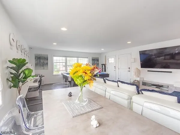a living room with furniture flowerpot and a flat screen tv